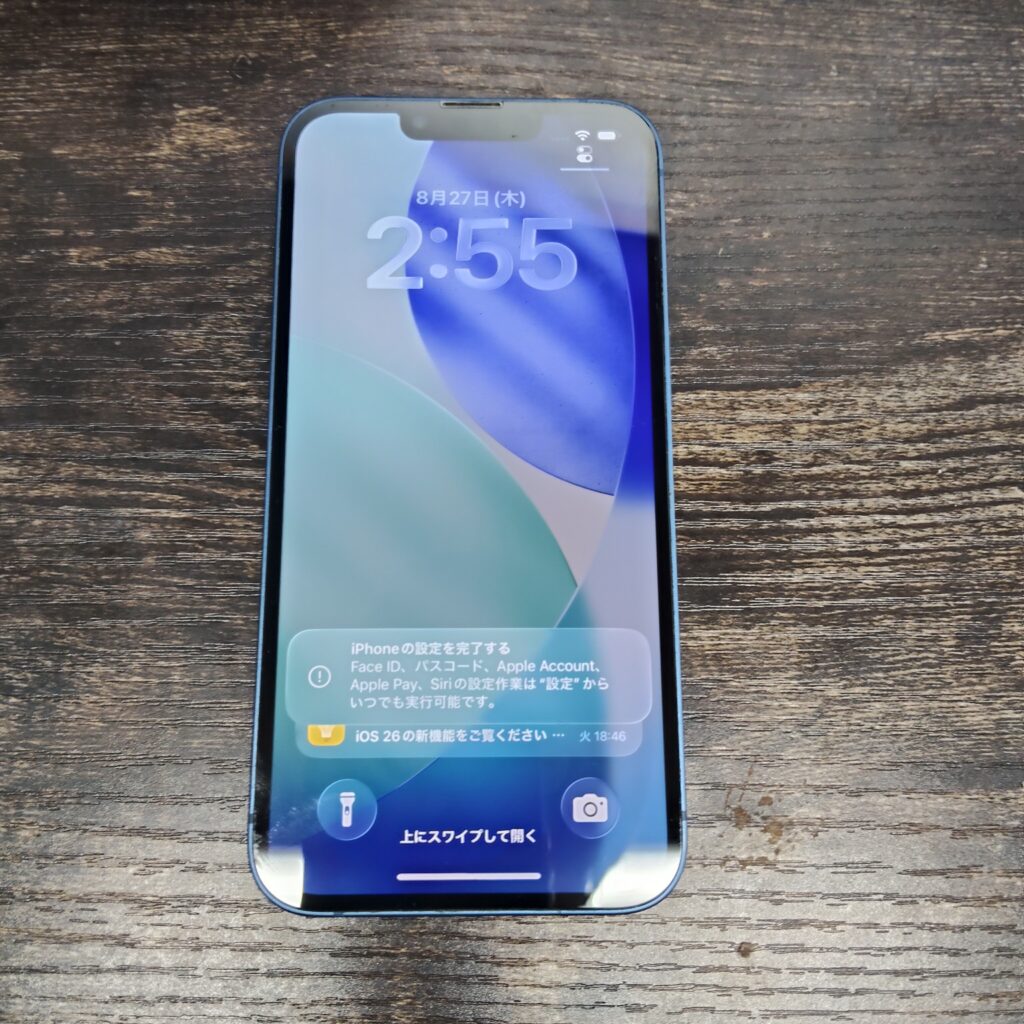 木目のテーブルに置かれた青色のiPhone 13